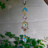 The turquoise Tree of Life Crystal Suncatcher with greenery in the background.
