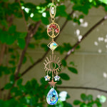 The carnelian Tree of Life Crystal Suncatcher with greenery in the background.