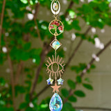 The carnelian Tree of Life Crystal Suncatcher with greenery in the background.
