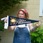 The Alderaan Pennant - Woolen Cotton Pennant being held in front of a cream-colored brick wall with greenery.