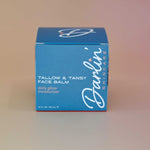 A blue jar of Darlin' Skincare Tallow & Tansy Face Balm daily glow moisturizer on a pink background.