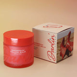 Red jar of magnesium balm with a matching box on a beige background