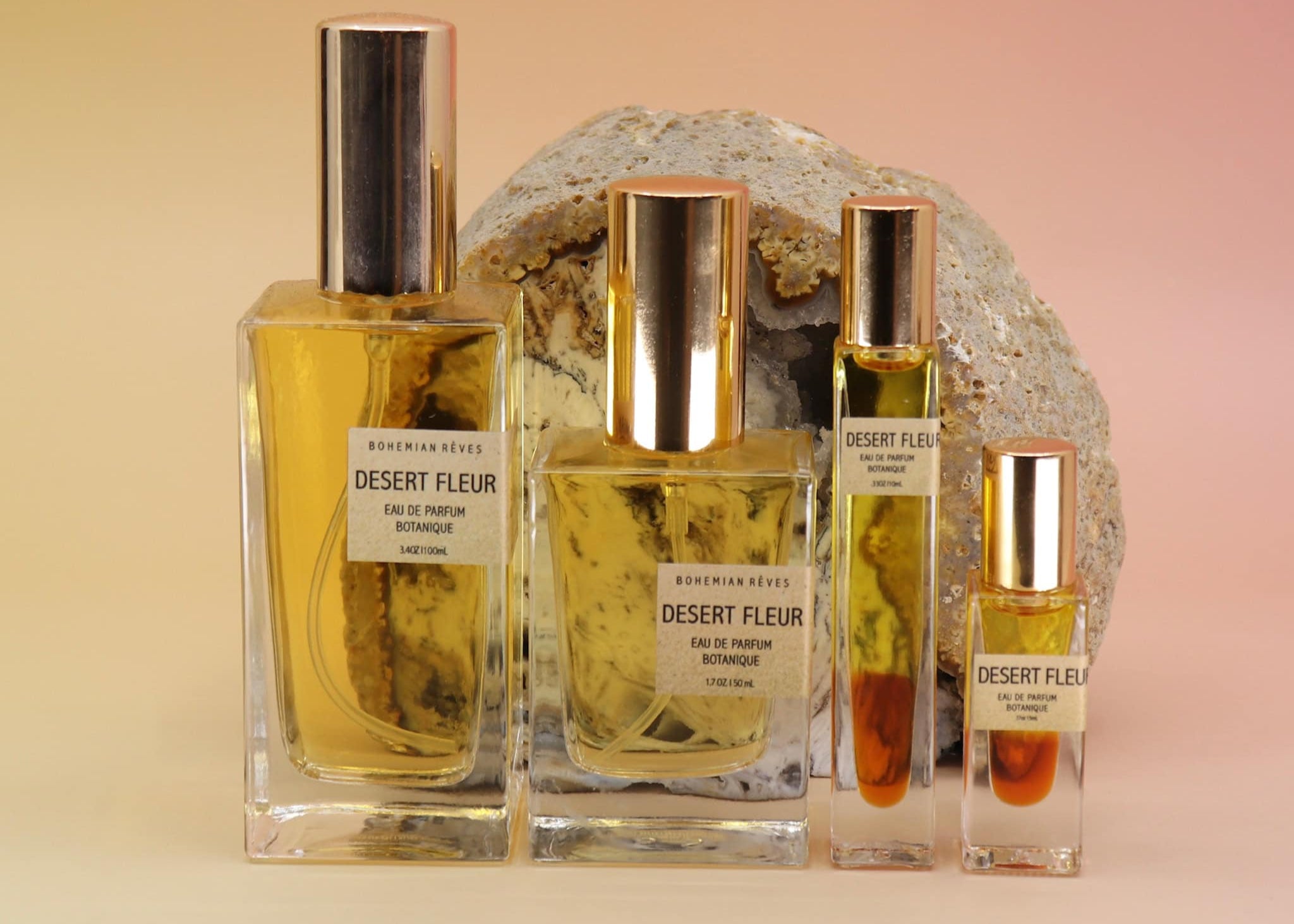 Four bottles of Desert Fleur perfume on a beige background