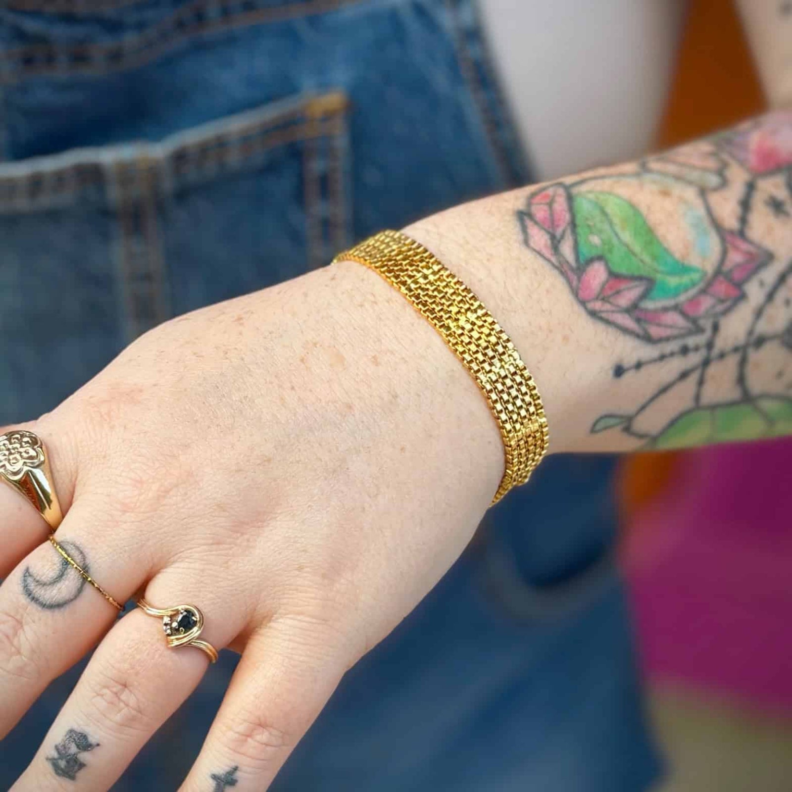 Gold bracelet shown with denim overalls and boho tattoos
