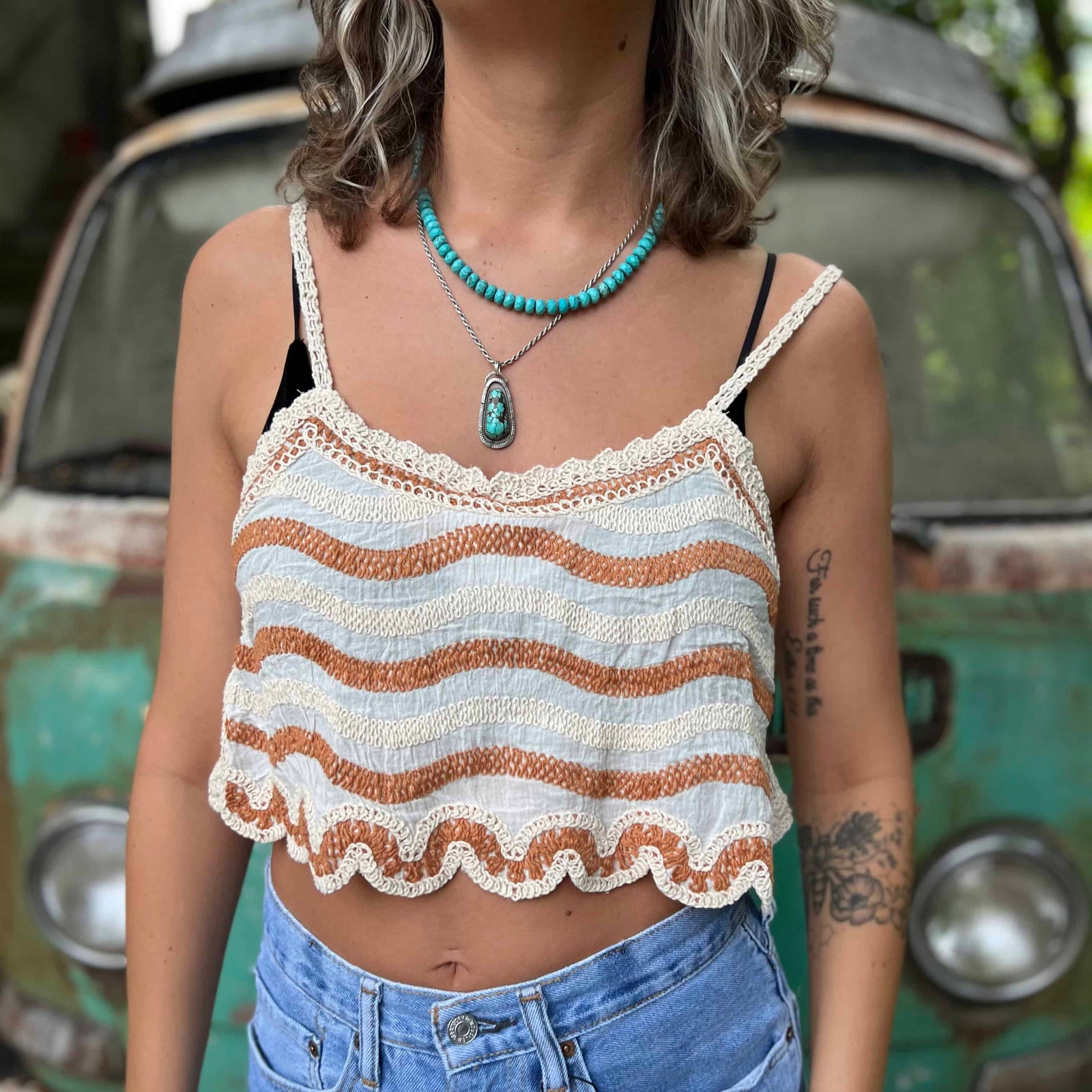 Model wearing embroidered cotton-linen crop tank top with orange stripes detail and scalloped hem