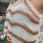 Close-up of boho embroidered crop top with floral stitching and scalloped edge paired with turquoise jewelry.
