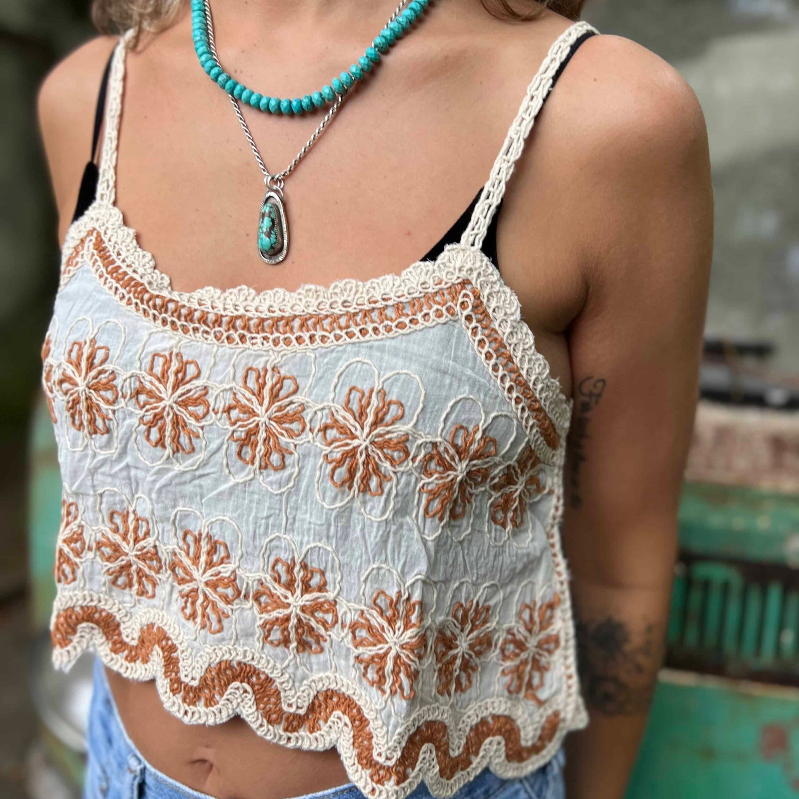 Open crochet lace front of boho crop tank top in ivory – model showing breathable fabric design close up view of the tank top and the orange flowers