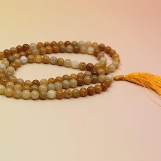 Golden Healer 108 Mala Necklace on pink and orange background