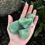 Rough Green Aventurine in palm of hand over ground