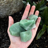 Rough Green Aventurine in palm of hand over ground