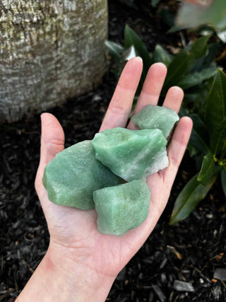 Rough Green Aventurine in palm of hand over ground