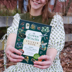 A woman holding the Green Witch's Sticker Book by Arin Murphy-Hiscock.