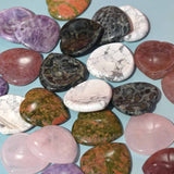 A collection of heart-shaped worry stones in various colors and patterns, displayed on a blue surface.