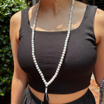 model wearing a black tank top in front of greenery with a howlite mala around her neck