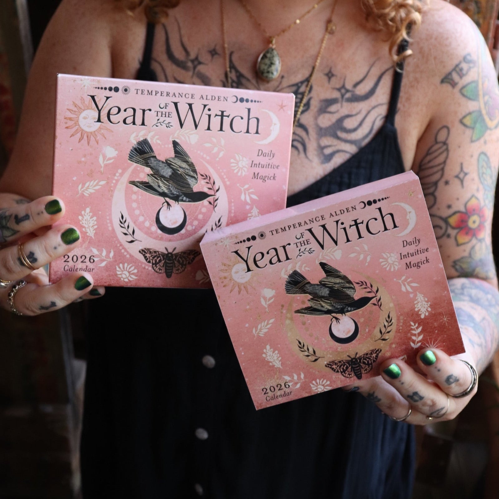 Someone holding two of the Year of the Witch 2026 Day-to-Day Calendars up in front of them.