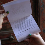 Someone holding the Year of the Witch 2026 Day-to-Day Calendar up in front of a door, showing off the pages.