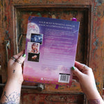 Someone holding the 2026 Lunar and Seasonal Northern Hemisphere Planner Calendar in front of a wooden door, showing off the back.