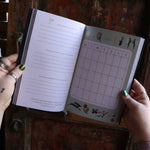 Someone holding the 2026 Seasons of the Witch Planner Calendar, showing off the pages.