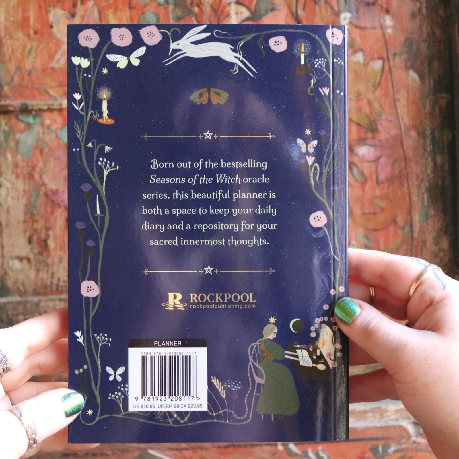 Someone holding the 2026 Seasons of the Witch Planner Calendar, showing off the back.