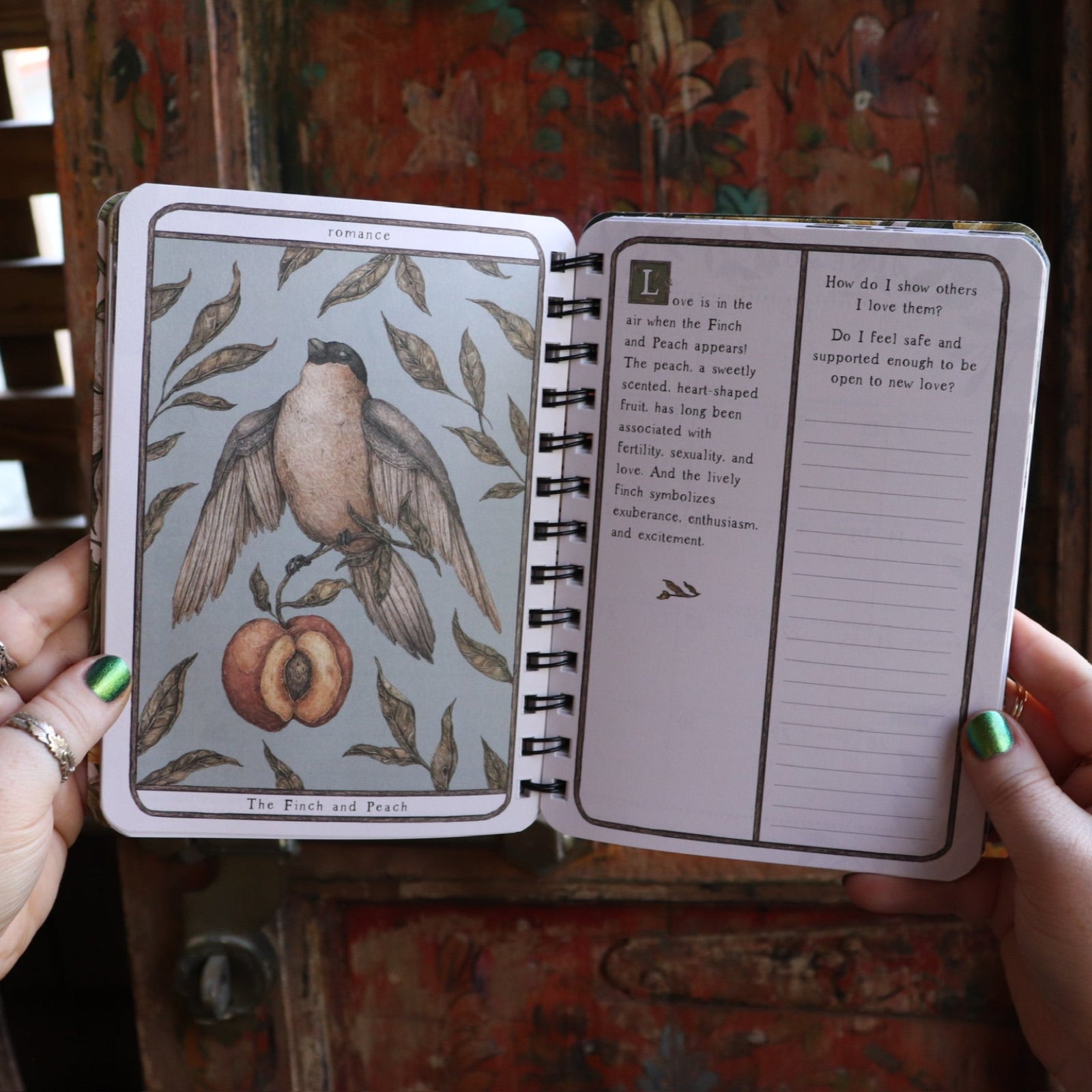 Someone holding the Woodland Wardens 2026 Weekly Planner in front of a door, showing off the pages.