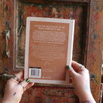 Someone holding the 2026 Moon Goddess Northern Hemisphere Planner Calendar in front of a wooden door, showing off the back.