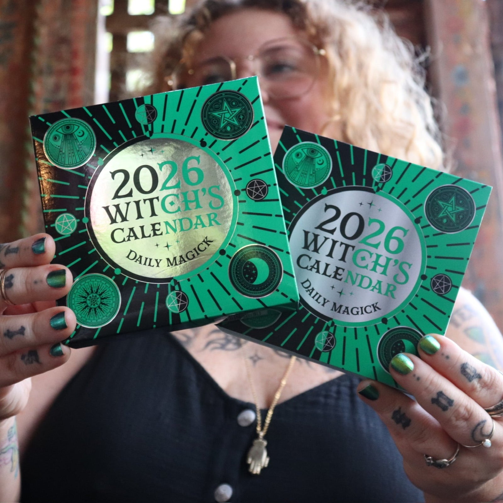 Someone holding two of the 2026 Witch's Calendar: Daily Magick Day-to-Day Calendars.