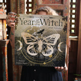 Someone holding up the Year of the Witch 2026 Wall Calendar.