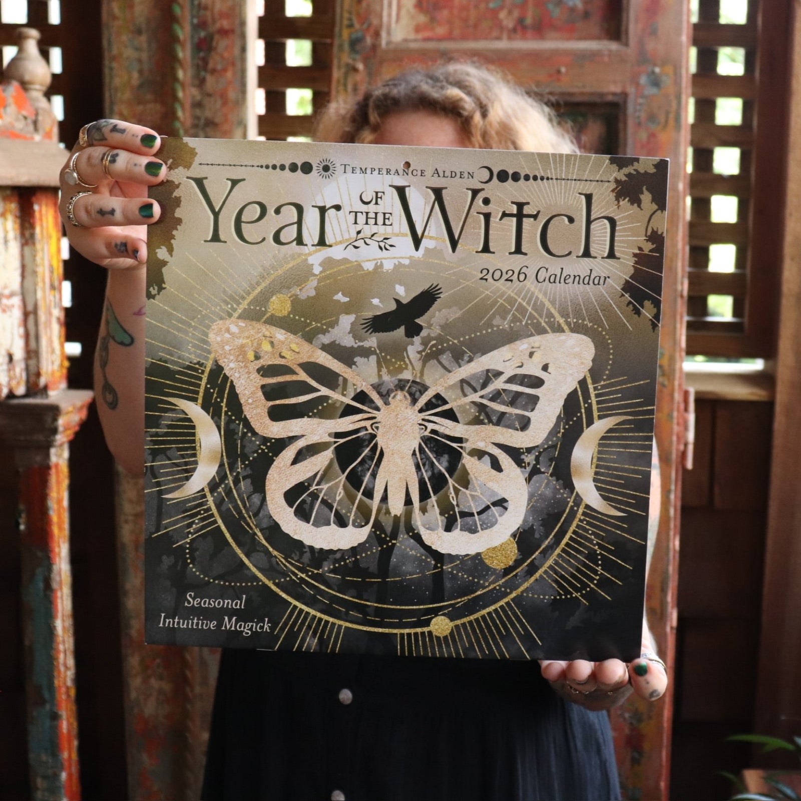 Someone holding up the Year of the Witch 2026 Wall Calendar.