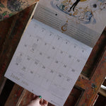 Someone holding up the Year of the Witch 2026 Wall Calendar, showing off the pages.