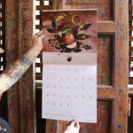 Someone holding up the Year of the Witch 2026 Wall Calendar, showing off the pages.