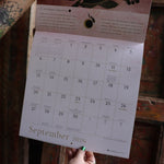 Someone holding up the Year of the Witch 2026 Wall Calendar, showing off the pages.