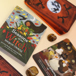 The contents of the Seasons of the Witch - Mabon Oracle Card Deck on a pink and yellow background.