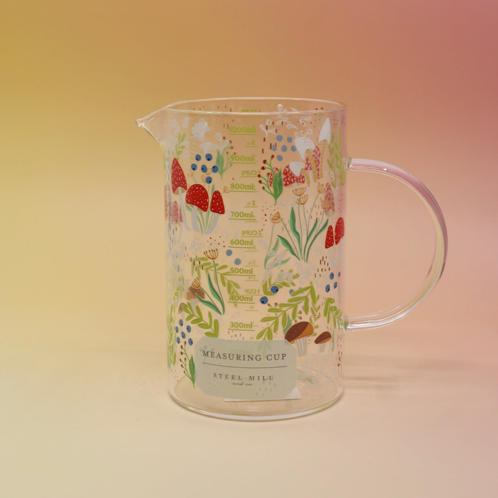 The Cottagecore Mushroom 1000 mL Measuring Cup on a pink and yellow background.