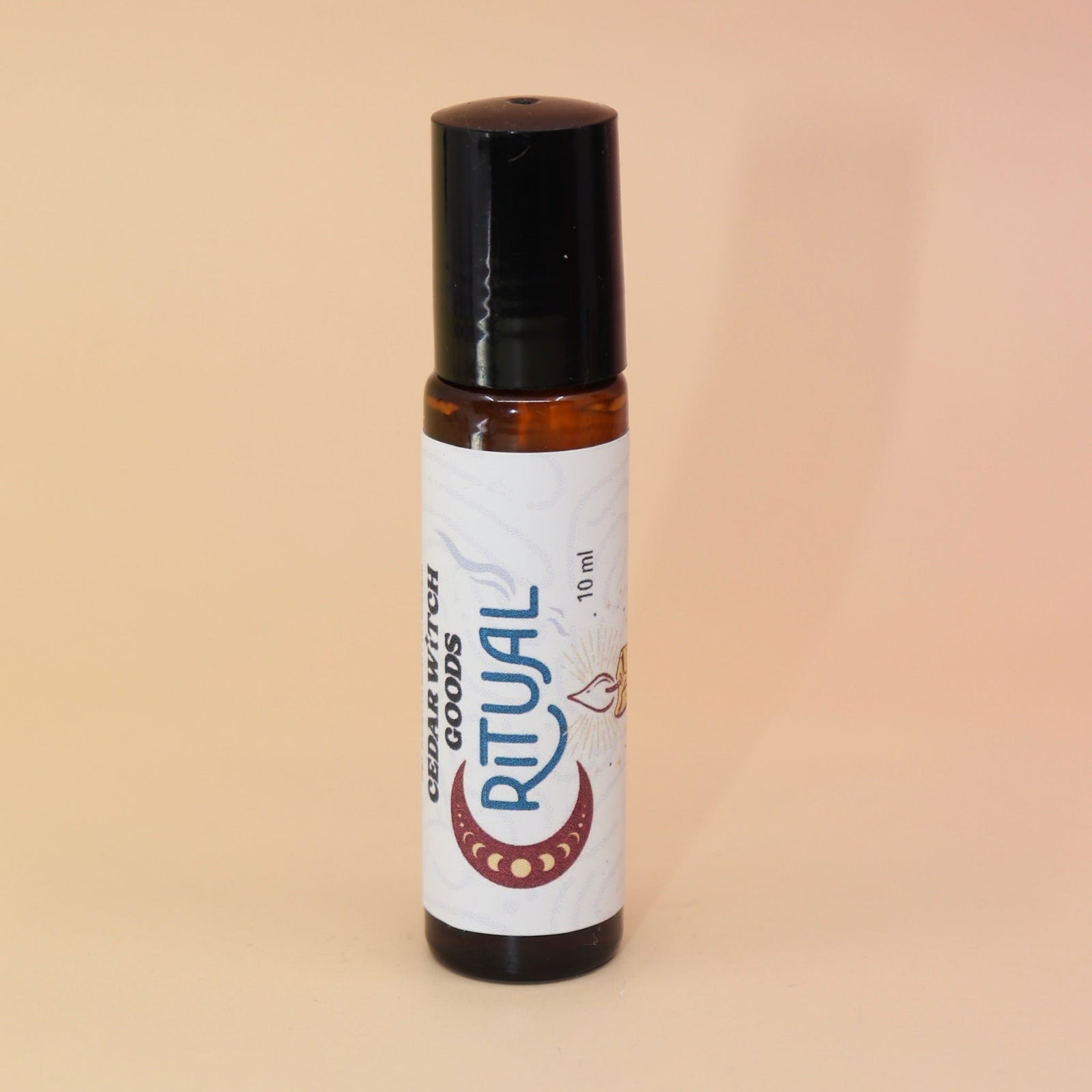 The Ritual 10ml Roll-On Perfume Oil on a pink and yellow background.
