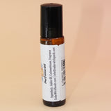 The Ritual 10ml Roll-On Perfume Oil on a pink and yellow background, showing off the back.