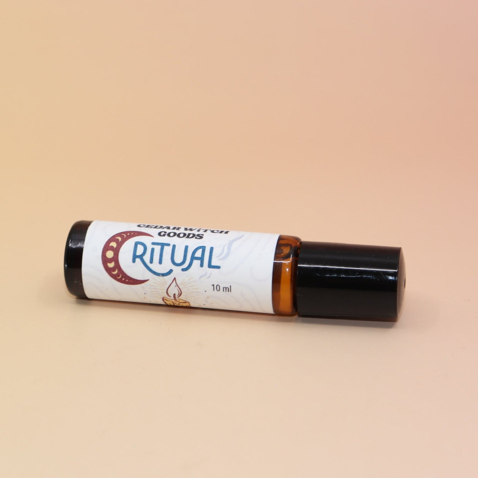 The Ritual 10ml Roll-On Perfume Oil on a pink and yellow background.