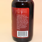 The Love Essence Organic Crystal Charged Energy Spray on a pink and yellow background, showing off the side.