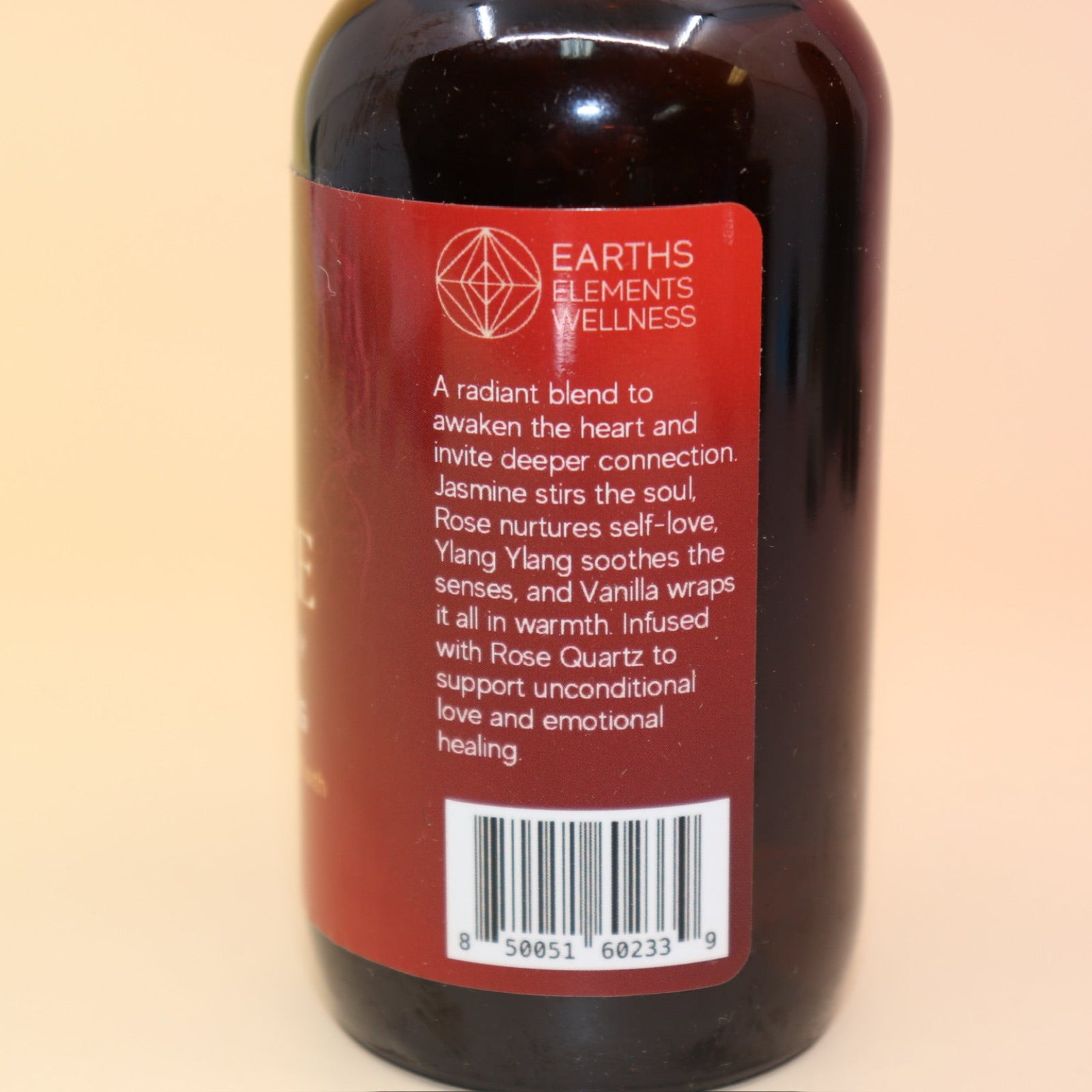 The Love Essence Organic Crystal Charged Energy Spray on a pink and yellow background, showing off the side.