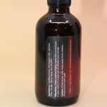 The Love Essence Organic Crystal Charged Energy Spray on a pink and yellow background, showing off the side.