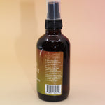 The Chakra Alignment Organic Crystal Charged Energy Spray on a pink and yellow background, showing off the side.