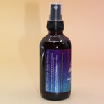 The Chakra Alignment Organic Crystal Charged Energy Spray on a pink and yellow background, showing off the side.