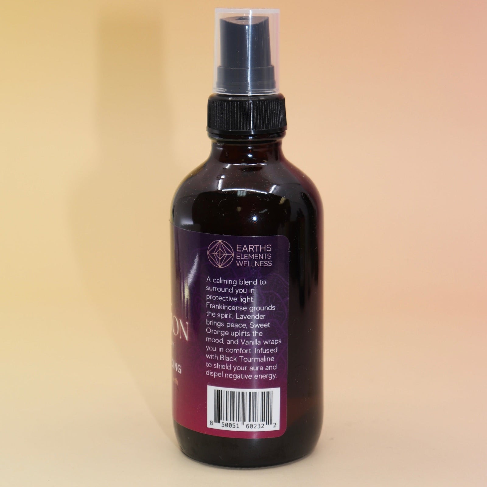 The Angel Protection Organic Crystal Charged Energy Spray on a pink and yellow background, showing off the side.