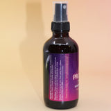 The Angel Protection Organic Crystal Charged Energy Spray on a pink and yellow background, showing off the side.