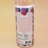 An up-close image of the back of the Love Spell Spiritual Cleansing Water 7.5 oz. on a pink and yellow background.