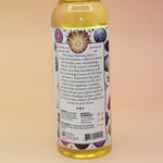An up-close image of the back of the Healing Energy Cleansing Water 7.5 oz on a pink and yellow background.