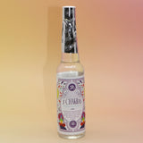 The 7 Chakras Spiritual Cleansing Water 7.5 oz on a pink and yellow background. 