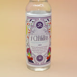 An up-close image of the 7 Chakras Spiritual Cleansing Water 7.5 oz on a pink and yellow background. 