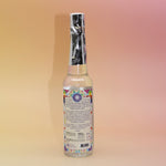The back of the 7 Chakras Spiritual Cleansing Water 7.5 oz on a pink and yellow background. 