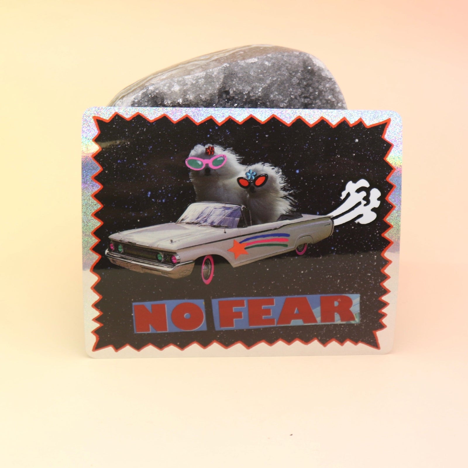 The No Fear Glitter Sticker against a crystal on a pink and yellow background. 