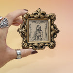 Someone holding the Deep Sea Diver Mini Vintage Framed Print in front of a pink and yellow background.